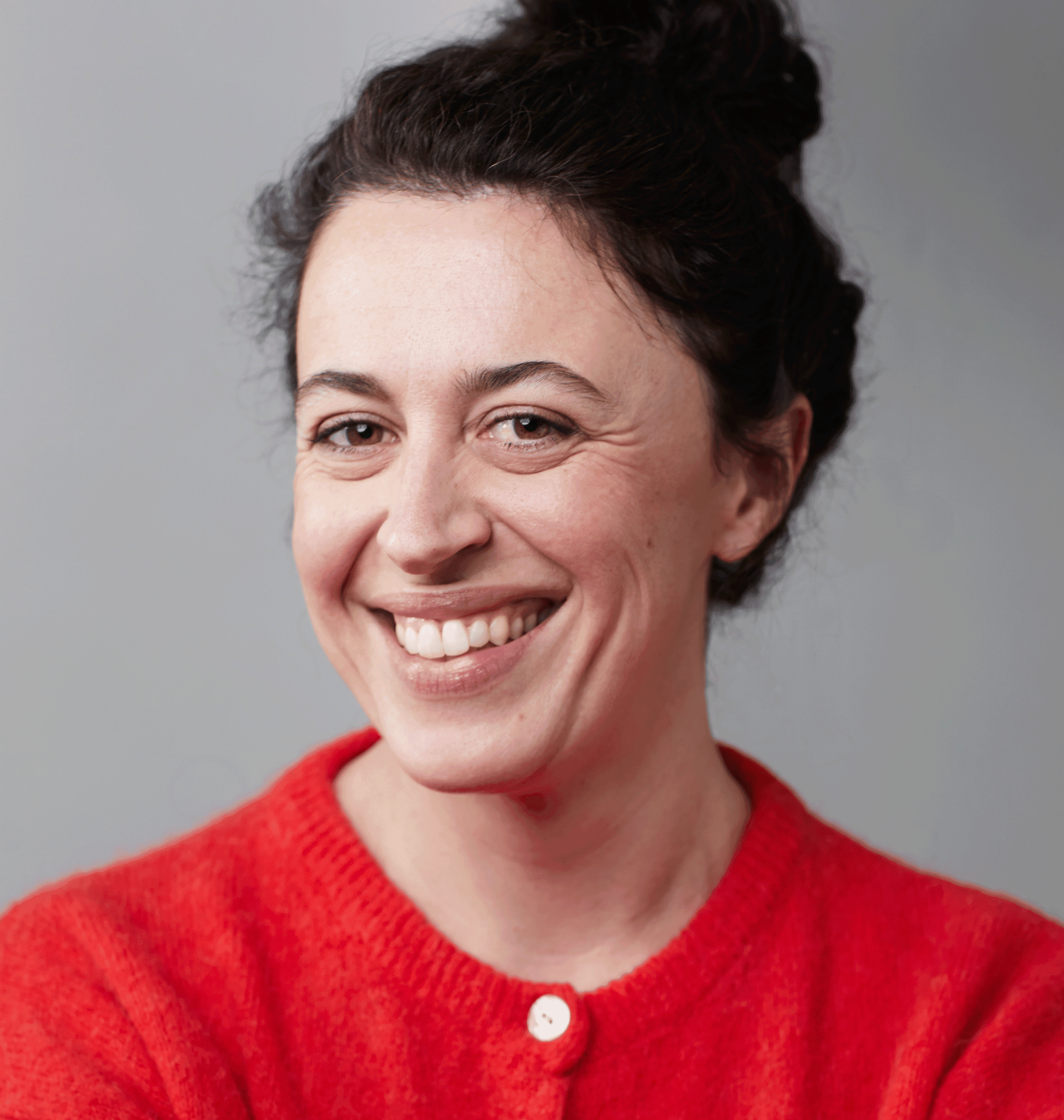 Portrait de Catherine Hughes souriante, cheveux foncés en chignon et un cardigan rouge