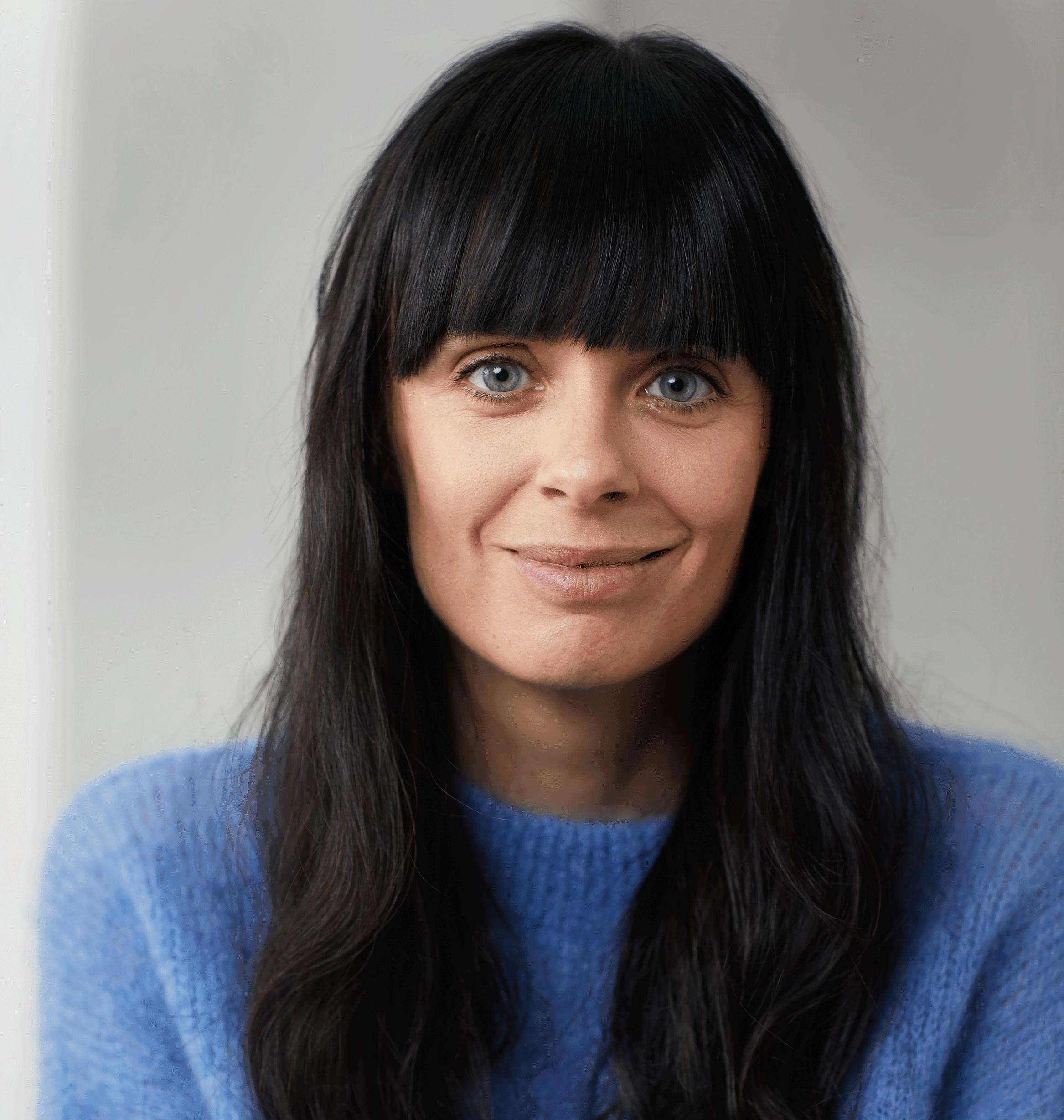 Portrait de Mélissa Lefebvre avec de longs cheveux foncés et une frange, portant un chandail bleu