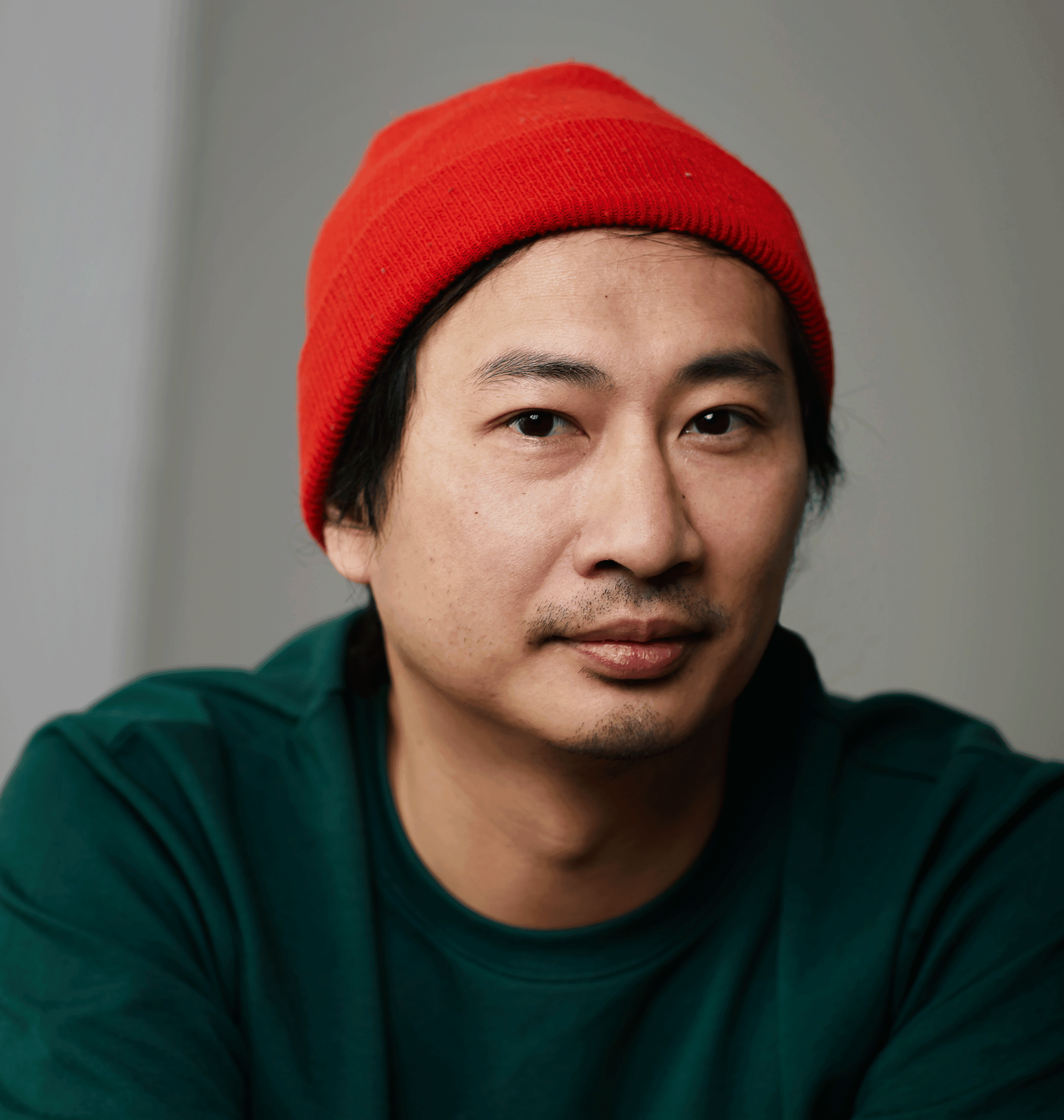 Portrait de Paul Tom portant une tuque rouge et un chandail vert